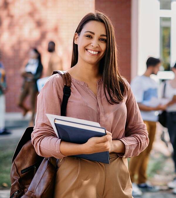 Woman Smiling Holding Books at School